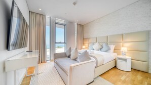 Una habitación de hotel moderna con una cama, mesita de noche, lámpara y un ventanal grande.
