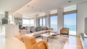 Una sala de estar moderna con un sofá, sillones, una mesita de centro y vistas al océano.