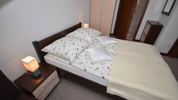 A neatly made bed with floral bedding, a bedside lamp, and a wooden headboard.