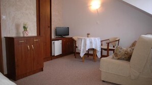 A small, cozy room with a kitchenette, a television, a table with chairs, and a sofa. - Dom Wczasowy Isabelle (Darłowo)
