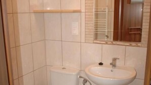 A bathroom with a toilet, sink, and mirror. - Dom Wczasowy Isabelle (Darłowo)