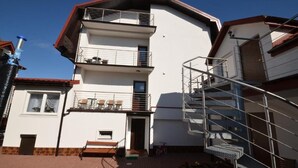 A multi-story building with balconies, a staircase, and a small outdoor seating area. - Dom Wczasowy Isabelle (Darłowo)