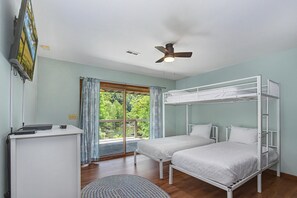 A room with a bunk bed, a desk with a computer, a ceiling fan, and a large window with a view of greenery. - River Vibes (Sevierville)