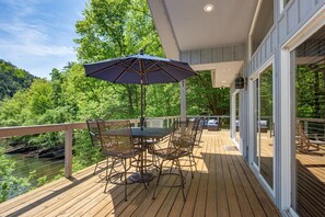 Eine Holzterrasse mit Gartenmöbeln, einem Tisch und einem Sonnenschirm.