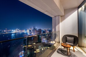 Un balcón con vista a la ciudad, una silla moderna y una mesita.