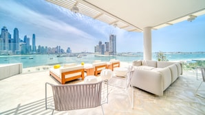 A modern outdoor lounge with a city skyline view, a pool, and a white outdoor sofa. - FIVE Palm Jumeirah: 4BR Penthouse w/ Private Pool (Dubai)
