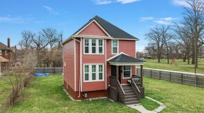 A two-story house with a front porch and a small staircase leading to the entrance.