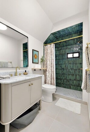 A modern bathroom with a vanity, toilet, shower, and a large mirror.