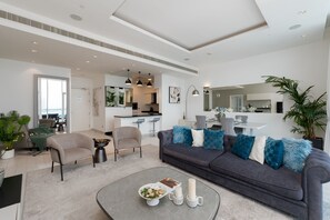 Ein modernes Wohnzimmer mit einem grauen Sofa, einem Couchtisch und einem Essbereich mit einem weißen Tisch und Stühlen.