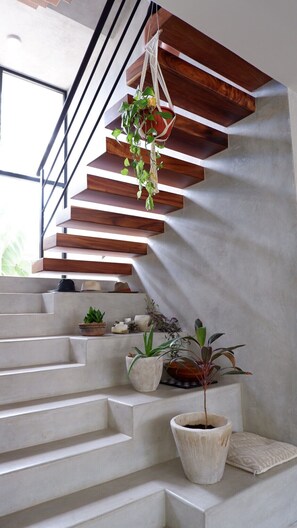 Eine moderne Treppe mit Holzbeschlägen und einem Makramee-Pflanzenaufhänger.