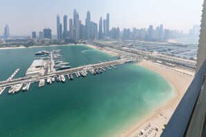 Eine Luftaufnahme einer Küstenstadt mit einem Yachthafen, Hochhäusern und einem Strand.