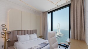 A modern hotel room with a bed, a desk, and a view of a cityscape. - Address JBR Elegant 2BR w/ Beach Access (Dubai)