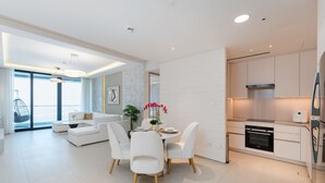 A modern living room with a dining area, a kitchen, and a large window. - Address JBR Elegant 2BR w/ Beach Access (Dubai)