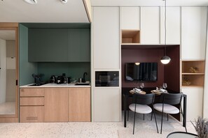 Una cocina compacta con zona de comedor, televisión integrada y un pequeño rincón de descanso.
