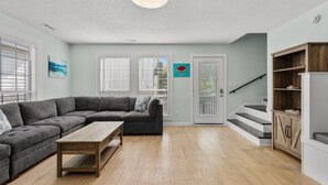 Ein Wohnzimmer mit Ecksofa, Couchtisch aus Holz, einer Treppe und einem Holzkabinett.