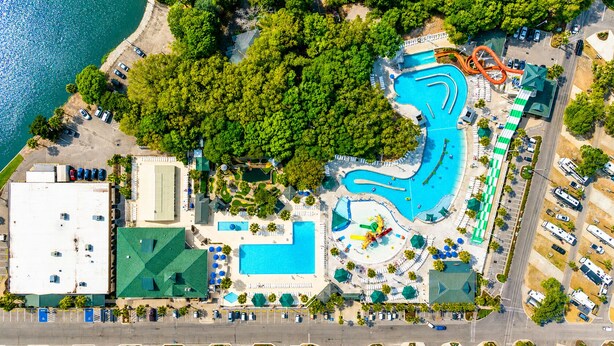 Eine Luftaufnahme eines Resorts mit mehreren Schwimmbecken, einem Wasserpark und einem Parkplatz.
