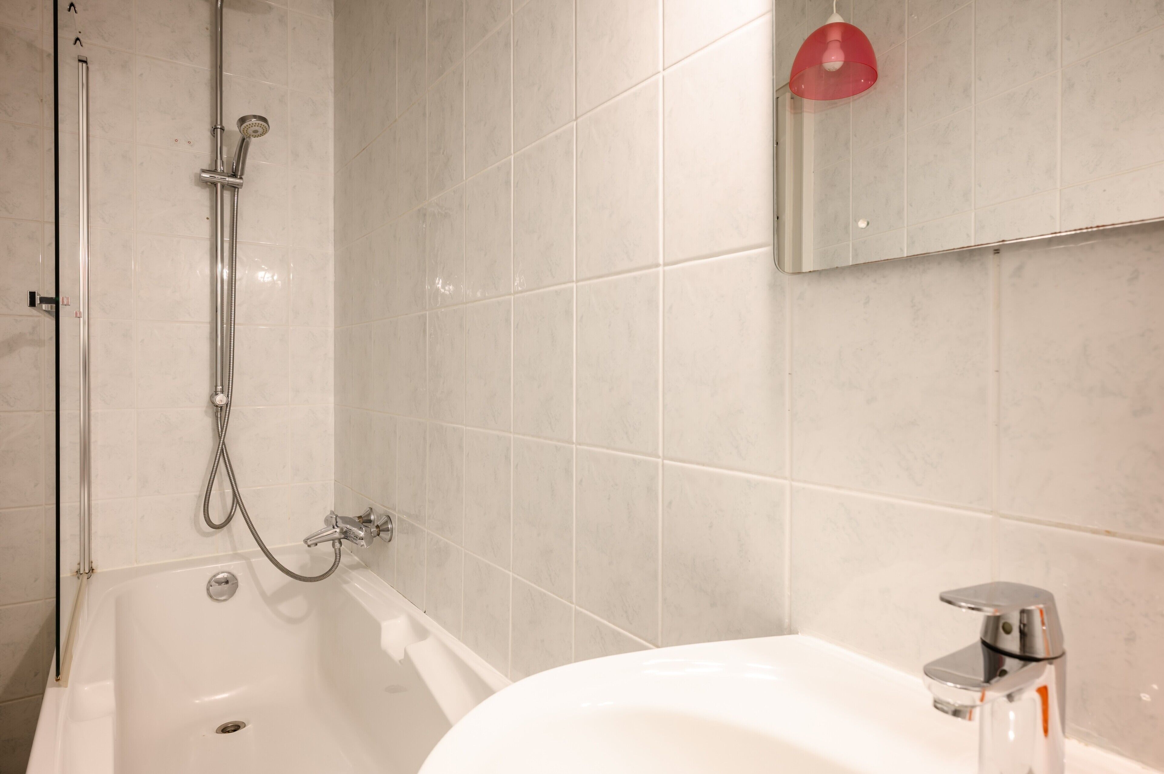 A bathroom with a bathtub, shower, and sink.
