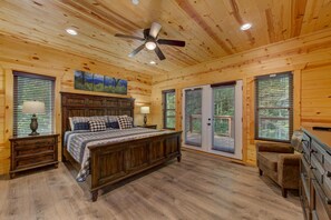 A wooden cabin bedroom with a bed, nightstands, a dresser, and a ceiling fan. - Smoky Mountain WOW (Gatlinburg)