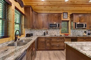 Eine Küche mit Holzausstattung, Granit-Arbeitsplatten, Edelstahlgeräten und einer Rückwand.