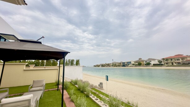 Un patio con mobiliario exterior, vista a la playa y una masa de agua.
