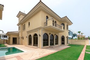Une grande maison à deux étages, dotée d’une piscine, d’un patio couvert et d’une pelouse bien entretenue.