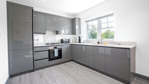Een moderne keuken met grijze kastjes, een inbouwoven en een raam dat natuurlijk licht biedt.