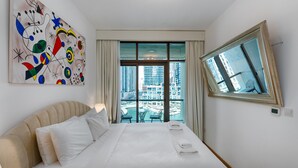 Camera d'albergo con un letto grande, un quadro appeso, vista sulla città dalla finestra e uno specchio.