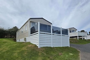 A mobile home with a covered porch and a fenced yard.