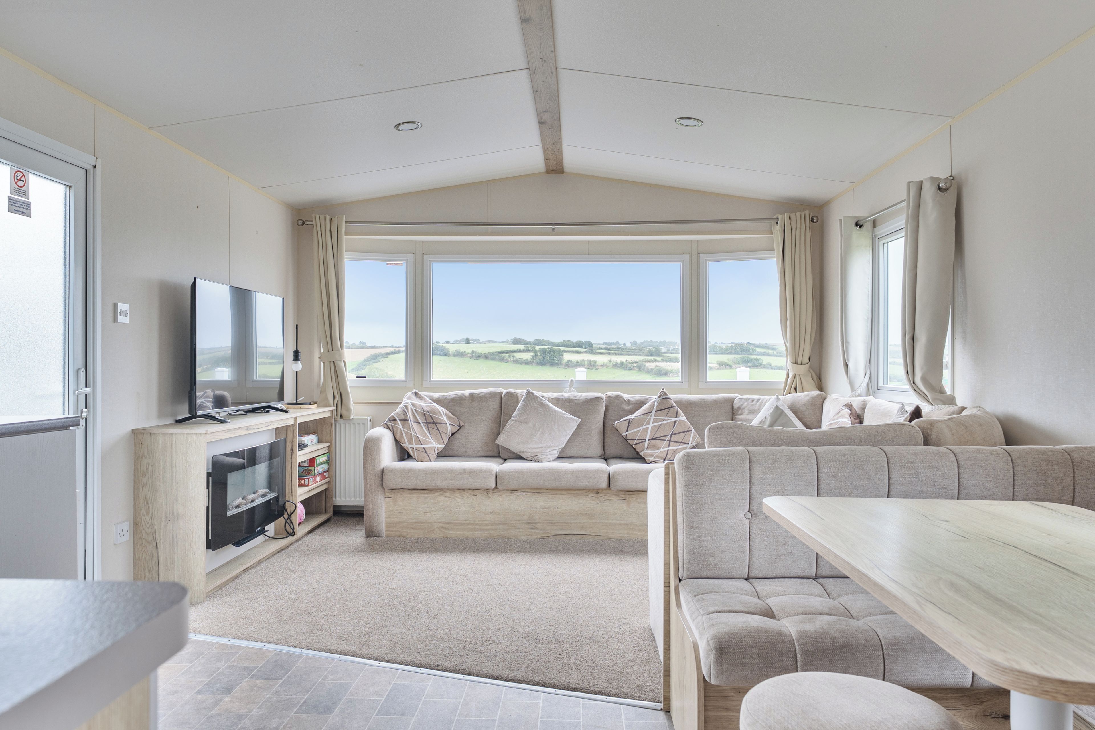 A room with a sofa, a television, and a view of the outdoors.