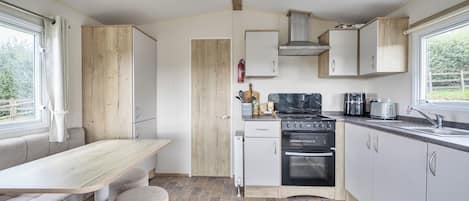 A compact kitchen with a dining area, a built-in oven, and a window providing a view of the outdoors.