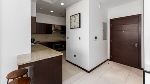 A modern kitchen with a granite countertop, dark wooden cabinets, and a built-in oven. - 2BR at the Palm | Balcony, Pool, Gym & Beach (Dubai)