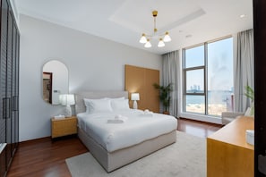 Ein modernes Hotelzimmer mit einem großen Bett, einem Schreibtisch, einem Spiegel und Blick auf den Strand.