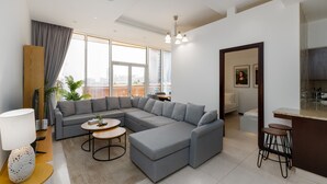 A modern living room with a sectional sofa, a round coffee table, and a bar area with stools. - 2BR at the Palm | Balcony, Pool, Gym & Beach (Dubai)