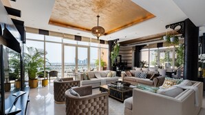 Un salón espacioso con un amplio sofá, una mesa de centro y vistas de la ciudad a través de grandes ventanales.