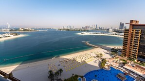 Un hotel frente al mar con playa, piscina y vistas del horizonte de la ciudad.