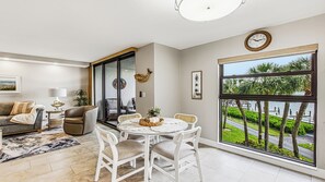 Ein modernes Wohnzimmer mit Essbereich, großen Fenstern und Blick ins Grüne.