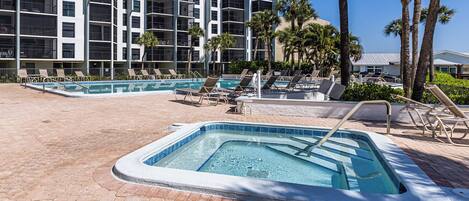 Un hôtel doté d’un espace piscine comprenant un jacuzzi et des chaises longues.