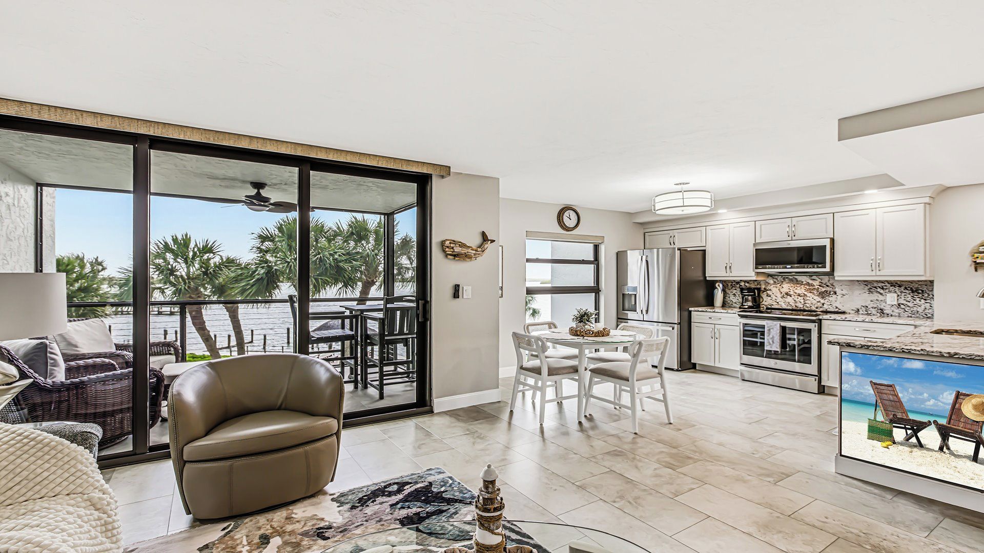A modern kitchen with white cabinets, a stainless steel refrigerator, and a large island.