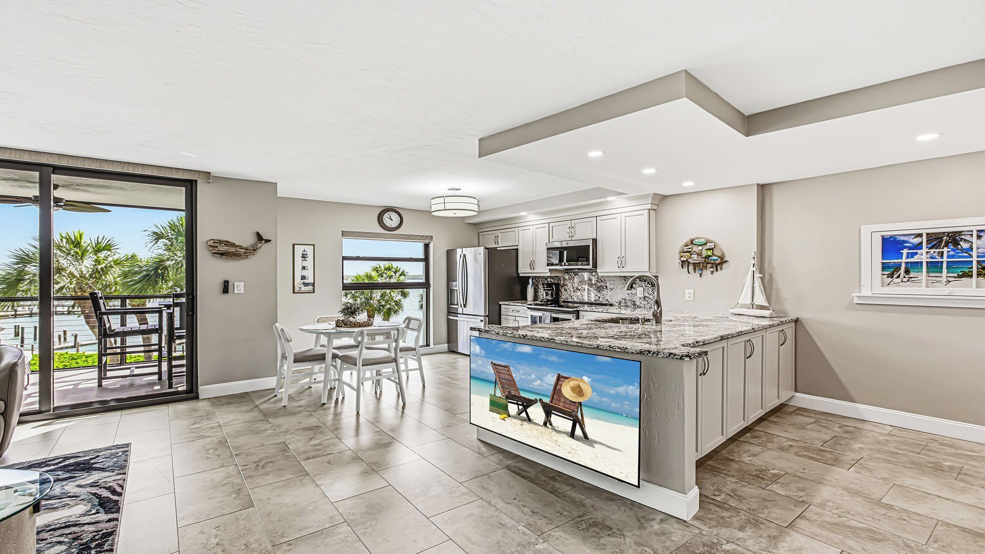 A modern kitchen with a large island, a dining area with a view, and a living space with a sliding glass door.