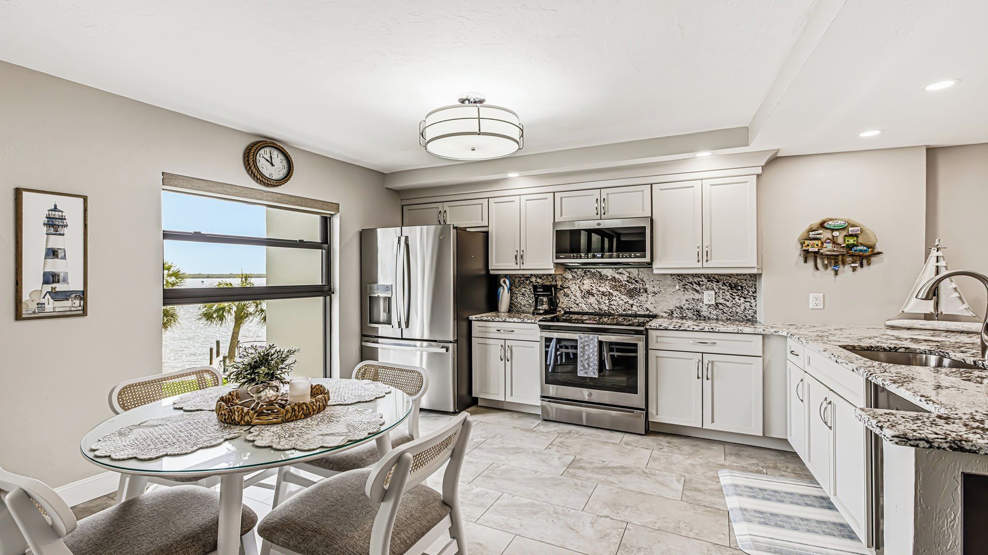 A modern kitchen with a dining area, large windows, and a view of the beach.