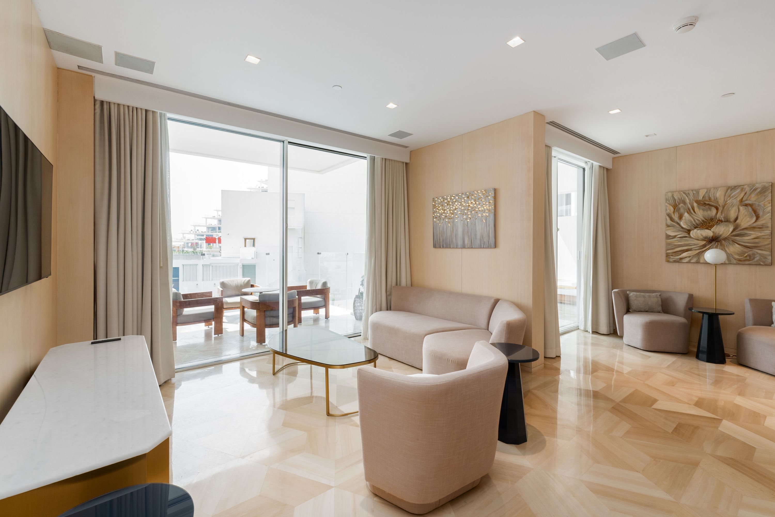 Un salon moderne comprenant un canapé, des fauteuils, une table basse et un téléviseur.