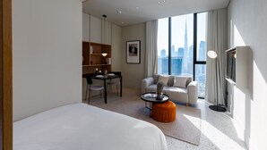 Un hotel moderno con una cama grande, un sofá, una mesa de comedor y vistas al horizonte de la ciudad.