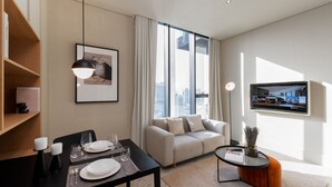 Una sala de estar moderna con comedor, sofá, televisor y vista a la ciudad.