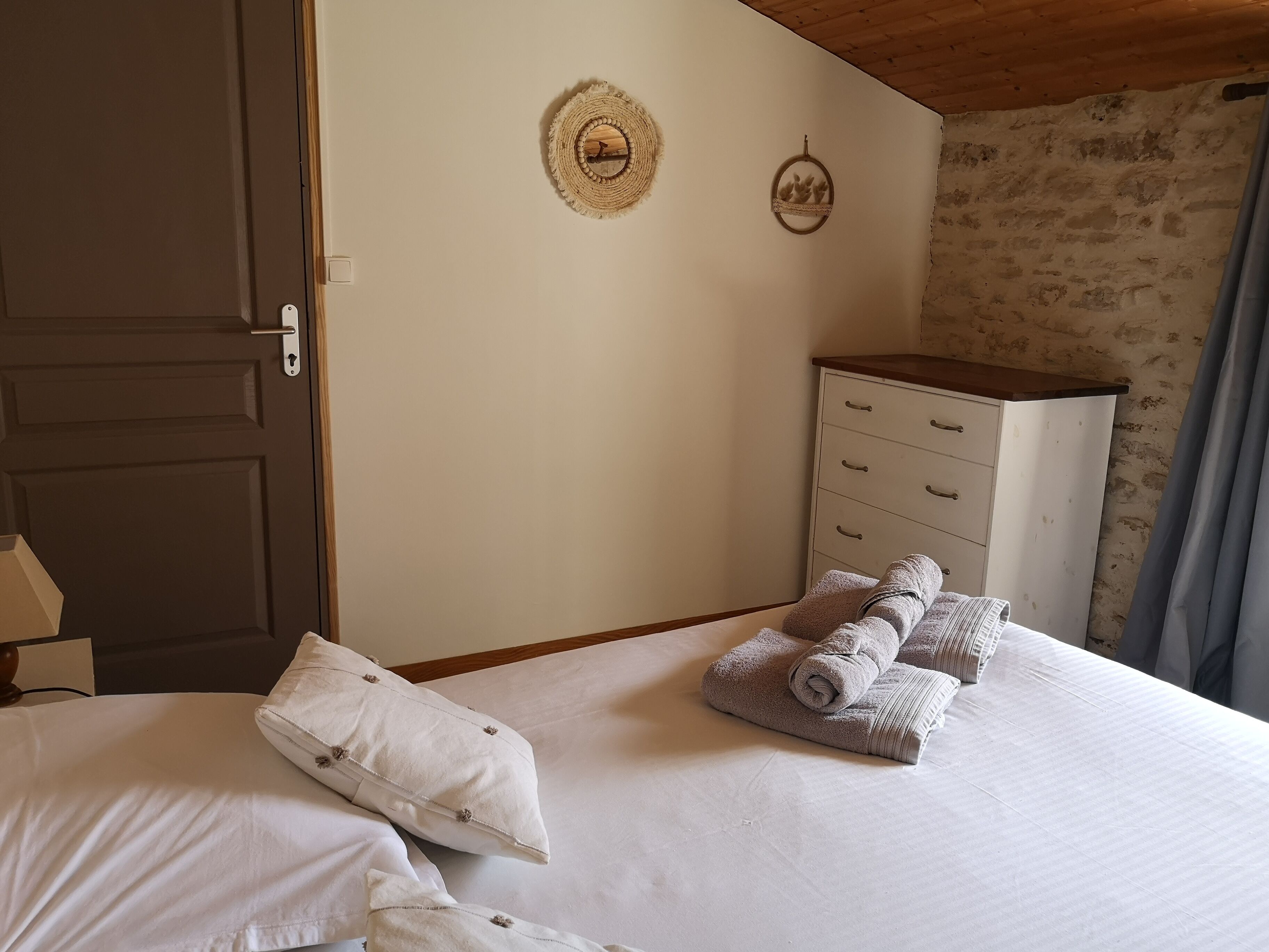 Quarto com cama, cômoda, porta e duas decorações na parede.