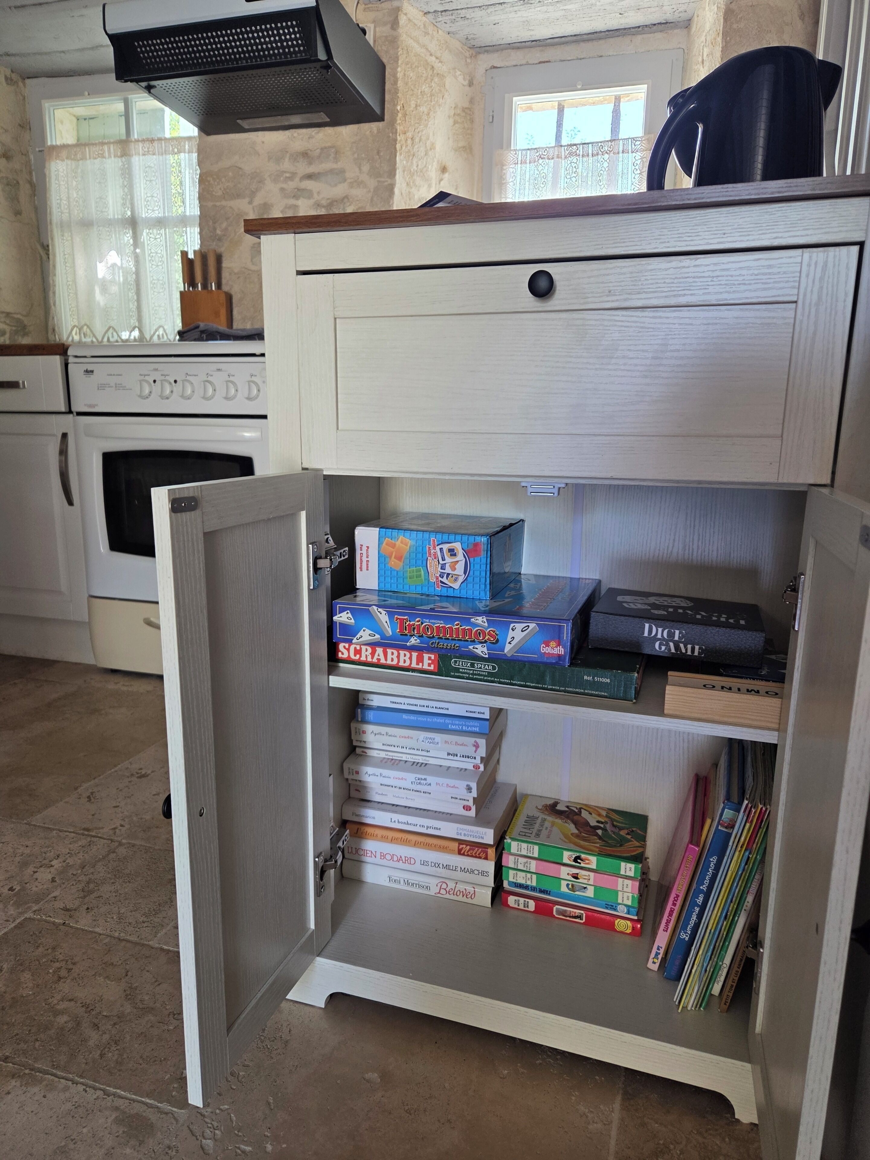 Una cocina con un armario empotrado que contiene juegos de mesa y libros.