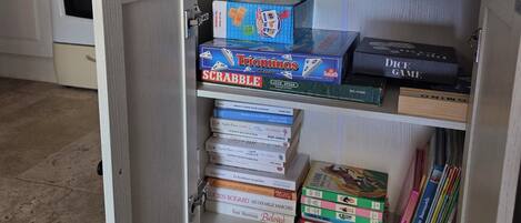Una cocina con un armario empotrado que contiene juegos de mesa y libros.