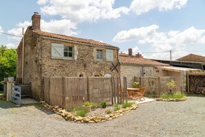 A rustic stone house with a tiled roof, a wooden fence, and a gravel driveway. - A charming vacation rental with a pool, nestled in the peaceful Vendée countryside. (Saint-Juire-Champgillon)