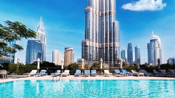 Una piscina con lettini e uno skyline urbano sullo sfondo.