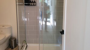 Un baño moderno con cabina de ducha de vidrio, inodoro y cubo de basura.