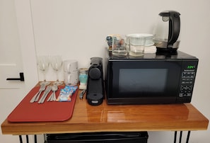 A kitchen counter with a microwave, a coffee maker, and various glassware and utensils. - New Hidden Creek Studio (Ucluelet)